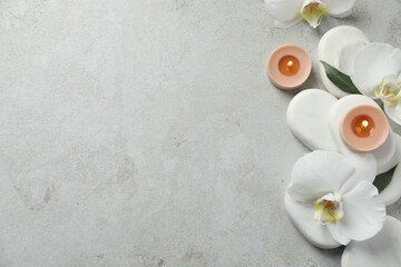 Flat lay composition with burning candles and spa stones on light grey table. Space for text