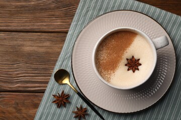 Cup of delicious eggnog with anise on wooden table, top view. Space for tex