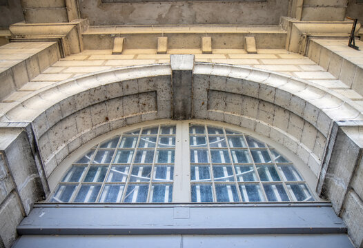 Entrance detail on late 19th century limestone building showing stone archway and keystone above an arched paned window