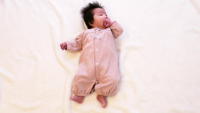 0歳3か月の乳児の赤ちゃんがこぶしを舐める様子の全身を撮影した動画