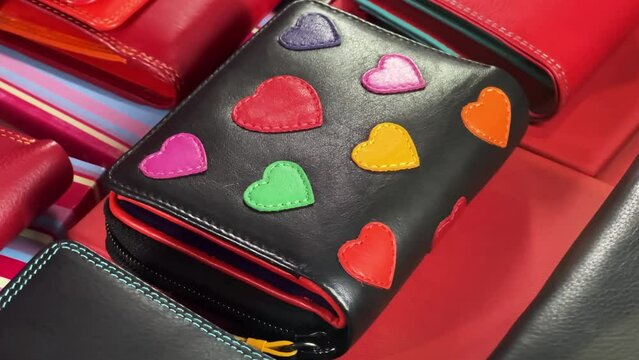 Leather wallet with sewn hearts lies on the window of an accessories store. Close-up