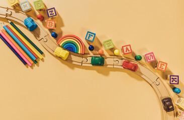 Wooden railway, blocks, rainbow, cars  on beige background. Preschool, elementary school education. Development games for kids. Educational daycare toys.