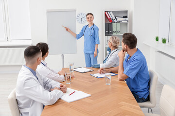 Doctor giving lecture near flipchart in conference room