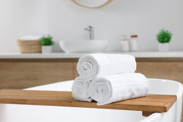 Rolled white towels on tub in bathroom. Space for text