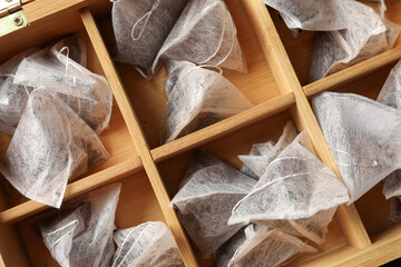 Fototapeta na wymiar Wooden box with pyramid tea bags, top view