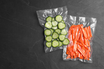 Sliced vegetables in vacuum packings on dark grey table, flat lay. Space for text