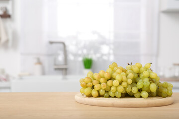 Fresh ripe grapes on wooden counter in kitchen, space for text