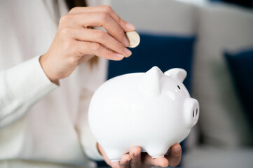 Asian woman putting coin in piggy bank. Save money and investment concept