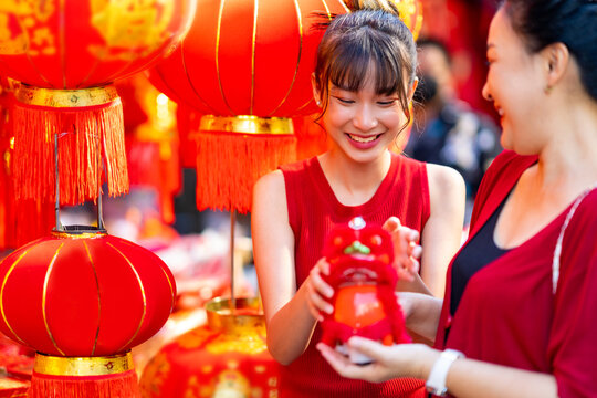 Asian woman mother and daughter holding shopping bag during buy home decorative ornament for celebrating Chinese Lunar New Year festival at Bangkok Chinatown street market. Chinese culture concept.