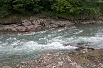 Fototapeta premium A mountain river in a stone bed, the summer period of the year.