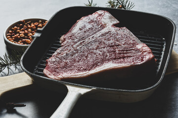 Thick Raw T-Bone or porterhouse Steak in a grill pan with peppers