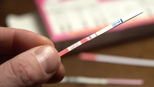Man Hold Negative HCG Pregnancy Test With his Fingers - Close Up
