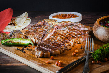 T-bone steak or porterhouse grilled in pieces on wood with hot pepper and salad