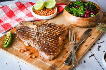 Grilled t-bone or porterhouse steak seasoned with rosemary in a rustic kitchen on a wooden board...