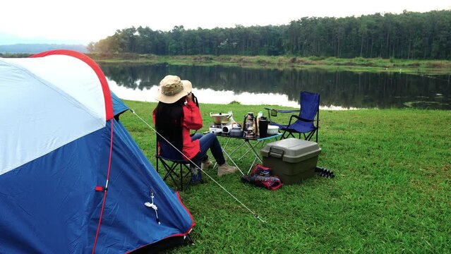 Woman taking photos with camera while camping in morning.