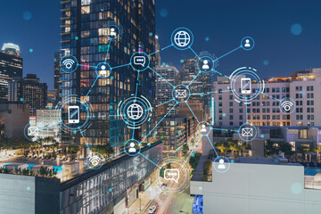 Illuminated cityscape of Los Angeles downtown at night, California, USA. Skyscrapers of LA city. Glowing Social media icons. The concept of networking and establishing new connections between people