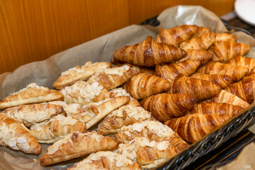 Wicker basket with fresh croissants on the buffet table. Fresh pastries at breakfasts, coffee...