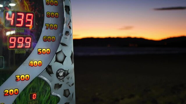 Arcade machine on the beach at a fair, blurry background, sunset time