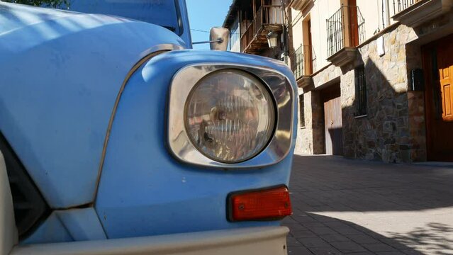 Old car in the foreground and stone houses in the background