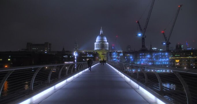 People Walking On London Millennium Bridge At Night. St. Paul's Cathedral In Backdrop. wide, POV