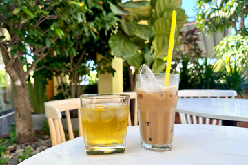 Vietnamese white cold coffee with milk and ice and green tea in terrace of cafe on table outdoors...