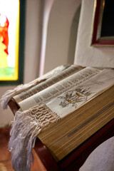 holy bible open on a pedestal inside the chapel. stained glass church background. natural lighting inside the church. holy book open. 