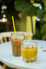 Vietnamese white cold coffee with milk and ice and green tea in terrace of cafe on table outdoors in exotic tropical country