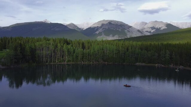Boat on pond mountains and forest flyover Rockies Kananaskis Alberta Canada