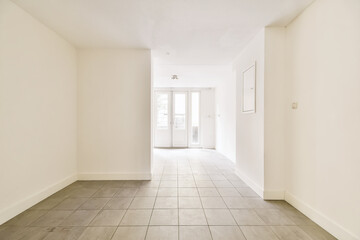 an empty room with white walls and wood flooring on the right, there is a door leading to another...