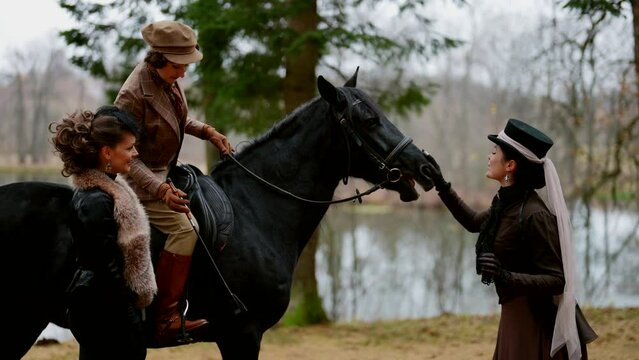 happy women dressed in vintage gown for horse riding on beautiful lake shore in autumn, portrait