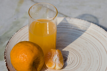 clementine or tangerine or orange fruit juice with a slice or segment of it kept on a plate....