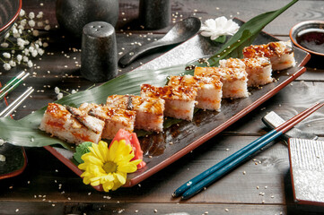 Sushi rolls with salmon and hot tea ceremony on black wooden table