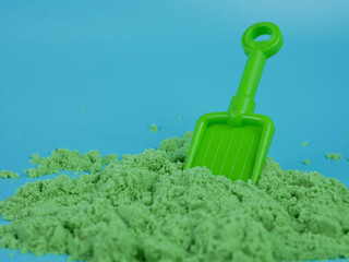 Green sand toy and shovel isolated on blue background
