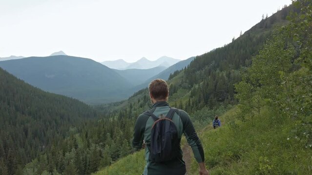 Hikers walking downhill on a trail in high altitude followed Rockies Kananaskis Alberta Canada