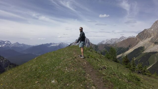 Hiker walking on top of mountain plane cheering Rockies, Kananaskis, Alberta Canada