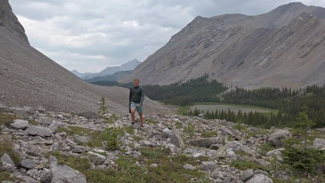 Hiker walking up mountain with lake and forest Rockies Kananaskis Alberta Canada