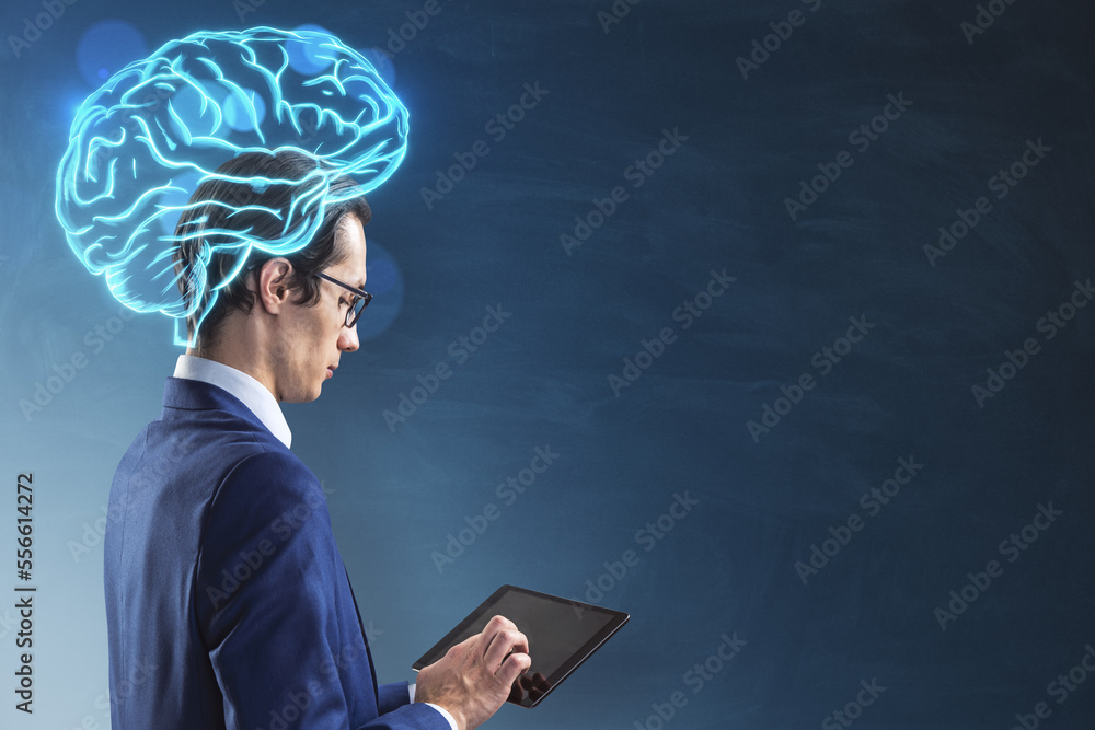 Poster businessman with tablet and glowing digital brain hologram standing on blurry chalkboard wall backgr