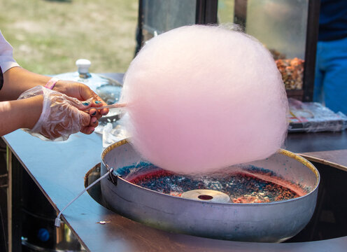 Cooking pink cotton candy on the city street.