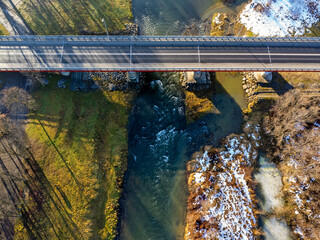 Aerial view. Road bridge from above. River, trees, meadow, cityscape. 