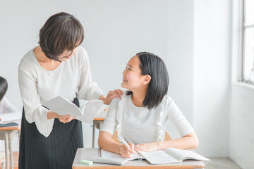 学校や塾で塾講師・先生に褒められてやる気になるアジア人の小学生・中学生・高校生の生徒（子供・女の子）
