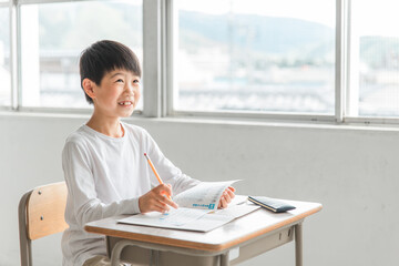 学校の教室・塾で楽しく勉強する笑顔の小学生の男の子（塾・夏期講習）
