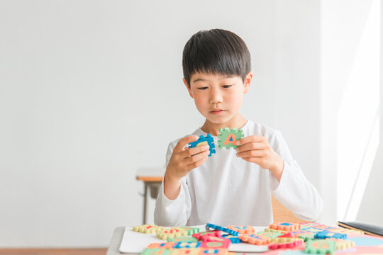 学校の教室でアルファベットのおもちゃを使って英語を勉強する小学生の男の子（低学年）
