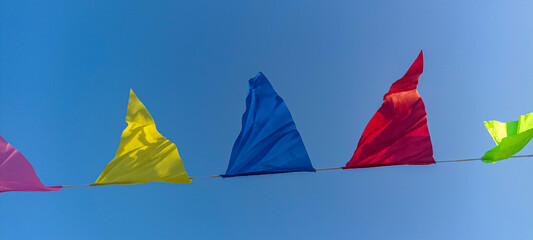 Buntings with colorful triangular flags against blue sky .
