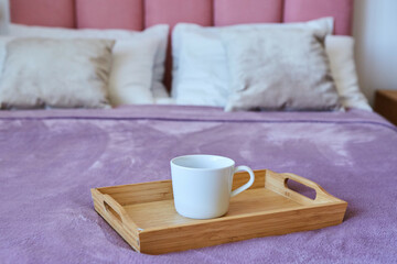 Fototapeta na wymiar A cup of tea on a tray is on the bed. Breakfast in bed.