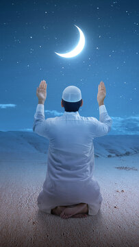 Rear view of a Muslim man sitting while raised hands and praying