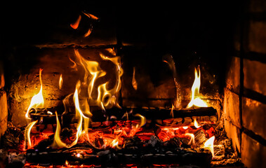 Flames of fire and hot coals of burned wood in the fireplace