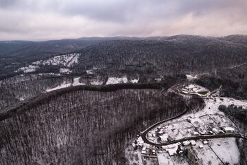 Aerial view of a forest covered in snow, in a mountainous rural area, from Romania. Captured with a drone, in winter conditions.
