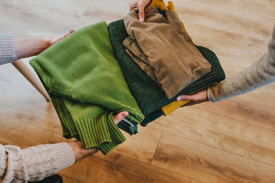 Hands of fashion designers holding clothes in workshop