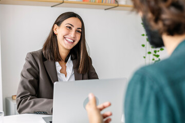 Happy recruiter interviewing candidate at desk in office