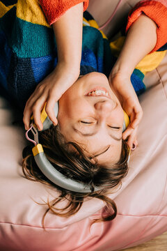 Happy girl listening to music through headphones lying on bean bag